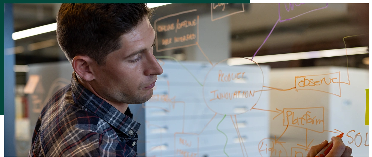 Caucasian casual businessman making notes brainstorming at glass wall in office. Casual office, business, brainstorm and work, unaltered.