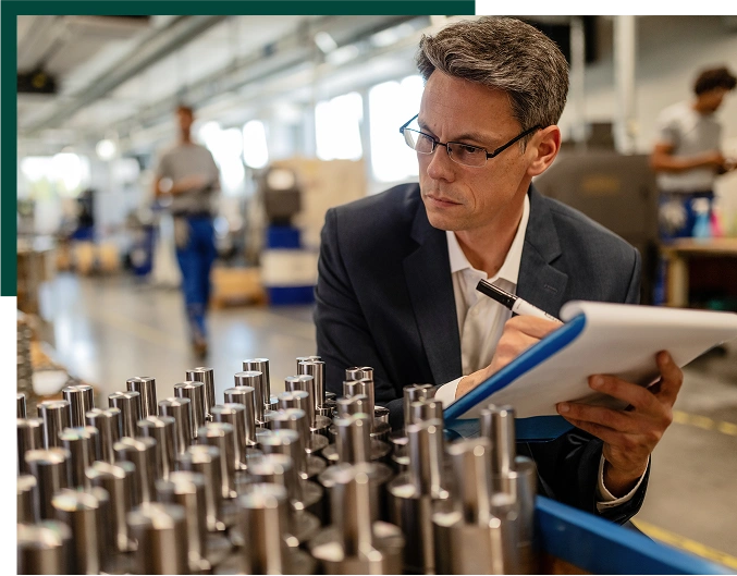 Quality control inspector writing reports while analzying manufactured steel rod cylinders in industrial building